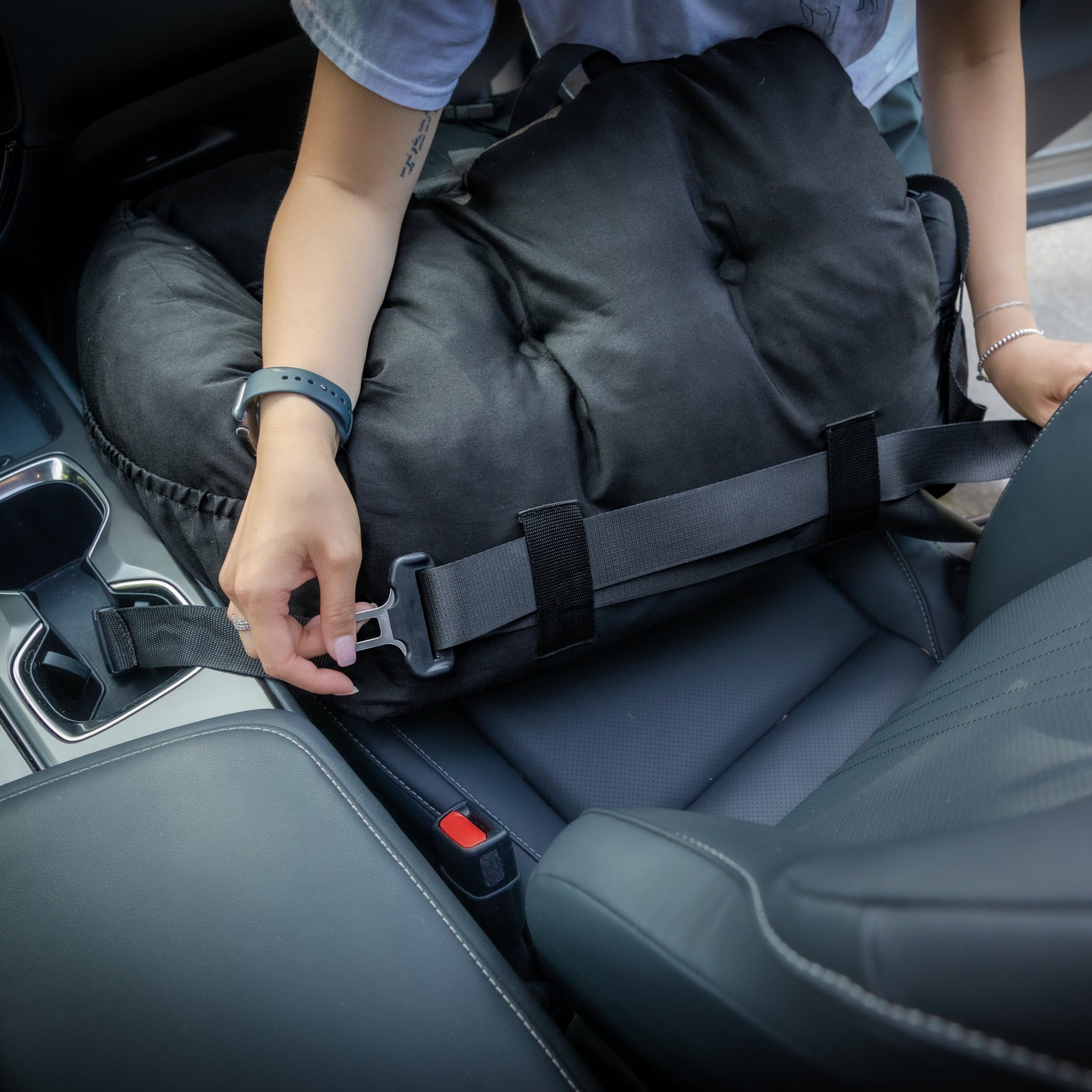 Person securing a black bag in a car seat